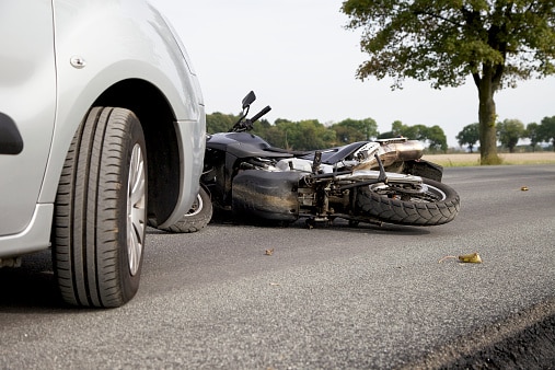 the remnants of a car hitting a motorcycle on the road
