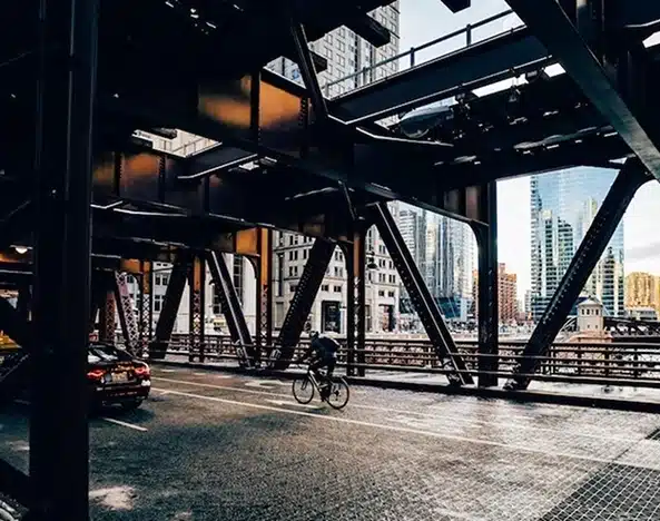 Chicago bicycle accident lawyer, image of bicyclist riding across a city bridge, Disparti Law Group Accident & Injury Lawyers