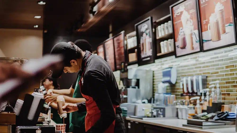 Starbucks unionization. image of starbucks employee drizzling caramel behind counter, Disparti Law Group Accident & Injury Lawyers
