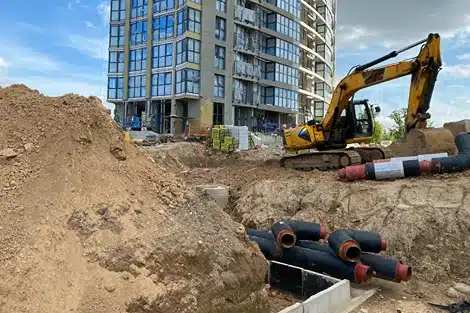 Rise in Trench Deaths, image of construction site trench next to building and construction truck