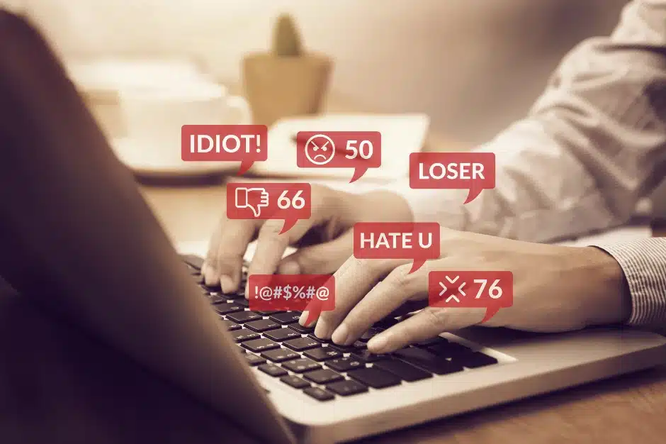 social media cyberbullying, image of someone at computer and hateful messages pop up in red boxes